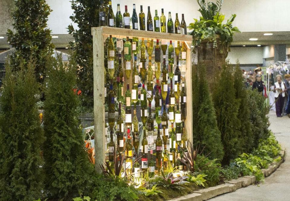 In this publicity photo provided by Chris H. Olsen, the Landscape Designer, Olsen, of Little Rock, Ark., created a decorative wall out of empty wine bottles by threading them onto metal poles inserted into a wooden frame. Olsen shares outdoor decorating ideas in his book "Chris H. Olsen's Five Seasons" (Leisure Arts, 2011). (AP Photo/Chris H. Olsen, Janet Warlick/Camera Work)