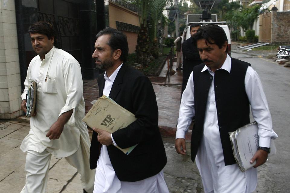 Samiullah Afridi (C), lawyer for doctor Shakil Afridi who ran a fake vaccination campaign to try to help U.S. officials find al-Qaeda chief Osama bin laden, arrives in court in Peshawar October 30, 2013. Lawyer Afridi has fled Pakistan after receiving threats from militants, relatives said on December 11, 2013. He went abroad after militants threatened to blow up his car and kill his family, a relative said. Picture taken on October 30, 2013. REUTERS/Khuram Parvez (PAKISTAN - Tags: POLITICS CIVIL UNREST CRIME LAW)