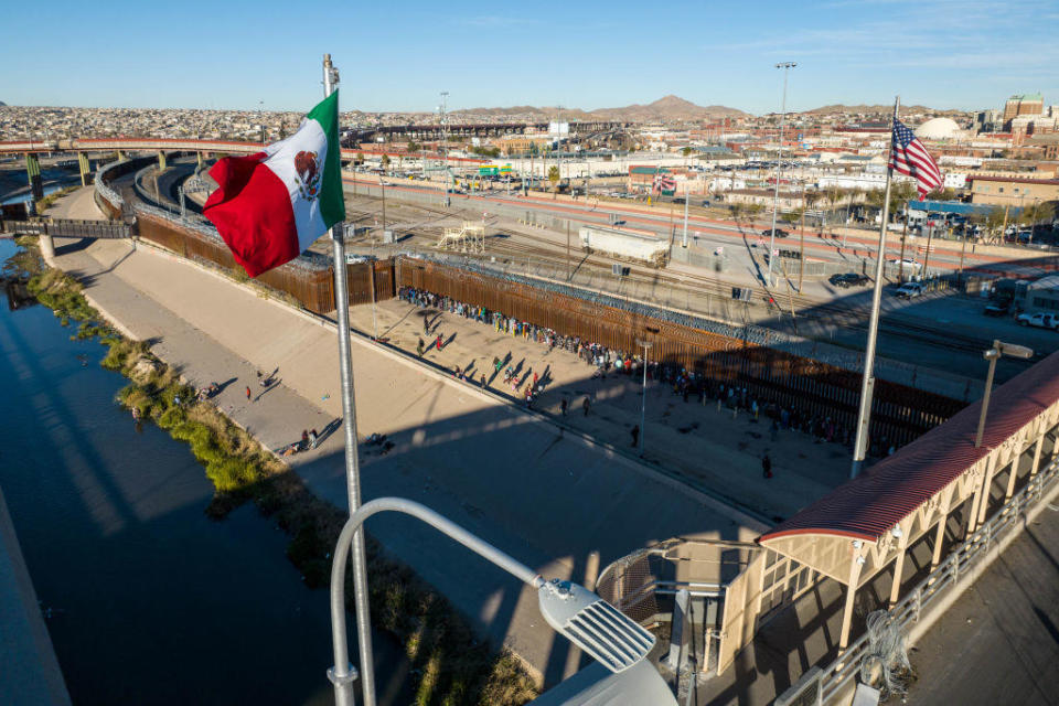 An aerial view of the Mexican and American flags fly over an international bridge as immigrants line up next to the U.S.-Mexico border fence to seek asylum on Dec. 22, 2022, in El Paso, Texas. / Credit: Getty Images