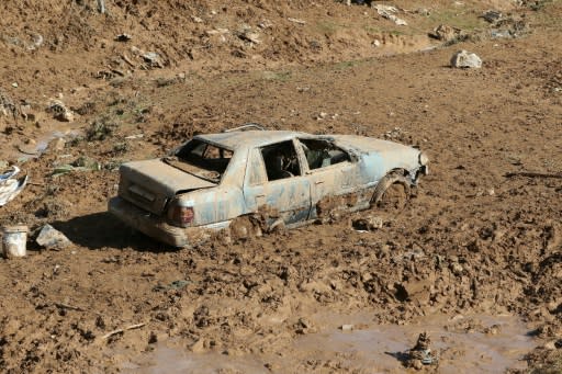 A picture taken on November 10, 2018 shows a car submerged in mud following flash floods in the city of Madaba near the capital Amman