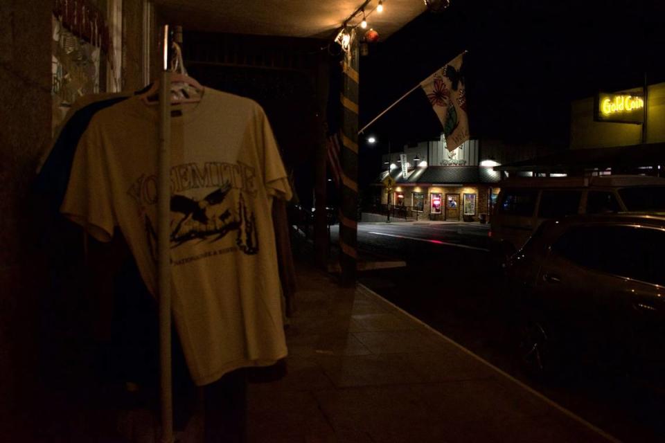 Camisetas con temática de Yosemite cuelgan a la venta el lunes por la noche en el exterior de Mariposa Marketplace, en la Central Yosemite Highway. Las pequeñas empresas del tramo de autopista en el que se encuentra la tienda dependen en gran medida del turismo.