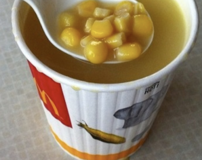 A cup of soup with corn, chicken, and pasta