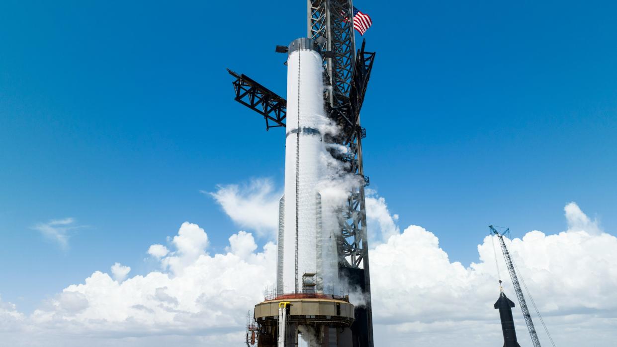  A SpaceX starship super heavy booster, white with frost, sits on a launch mount during a fueling test. 