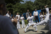 Britain's Chancellor of the Exchequer George Osborne, top right, watches youth who are part of the social project 'Luta Pela Paz,' or Fight for Peace, practice capoeira in the Mare slum complex in Rio de Janeiro, Brazil, Monday, April 7, 2014. More than 2,000 Brazilian Army soldiers moved into the Mare slum complex early Saturday in a bid to improve security and drive out the heavily armed drug gangs that have ruled the sprawling slum for decades. (AP Photo/Felipe Dana)