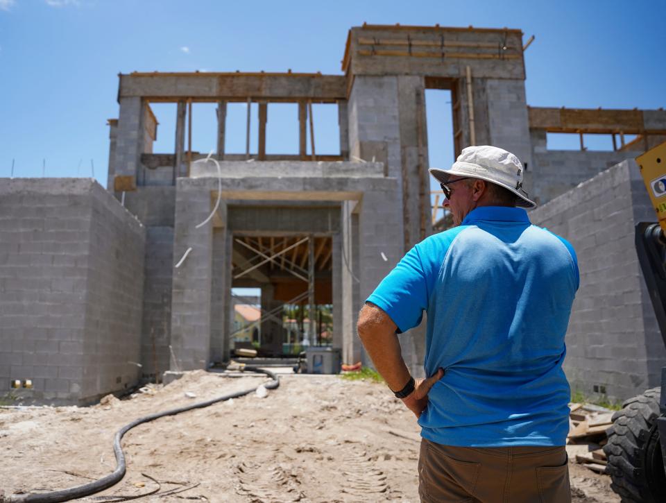 Chad Moore, regional director of construction at Stock Custom Homes, talks on the phone outside of a home the company is constructing at Bay Colony in Naples. Stock officials say it's often a struggle to find enough construction workers to meet the demand.