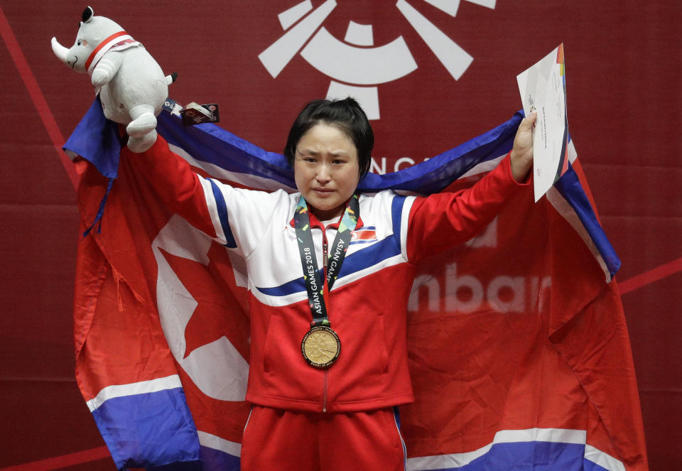 North Korean Ri Song Gum is teary eyed as she waves her national flag after winning gold the women's 48kg weightlifting games at the 18th Asian Games in Jakarta, Indonesia on Monday Aug. 20, 2018. (AP Photo/Aaron Favila)