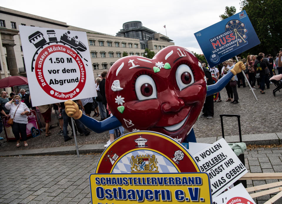 Vertreter des Schaustellerverbandes Ostbayern e.V. nehmen mit ihrem Maskottchen an der Kundgebung des deutschen Schaustellerbundes am Brandenburger Tor teil (Bild: Paul Zinken/dpa)