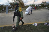 A soldier patrols a street while residents take items from local stores after Hurricane Otis ripped through Acapulco, Mexico, on Thursday, October 26, 2023. Many residents were taking basic items from stores to survive. Others left with pricier goods, in widespread rampages through the area's stores. (AP Photo/Marco Ugarte)