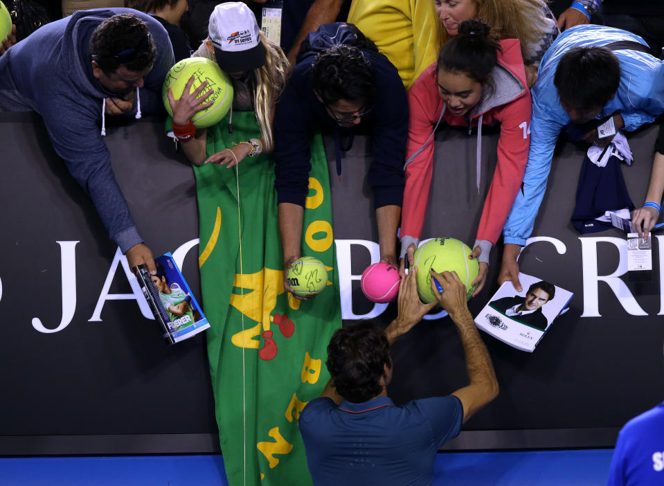 Roger Federer of Switzerland signs autographs for fans after defeating Andy Murray of Britain in their quarterfinal at the Australian Open tennis championship in Melbourne, Australia, Wednesday, Jan. 22, 2014.(AP Photo/Aaron Favila)