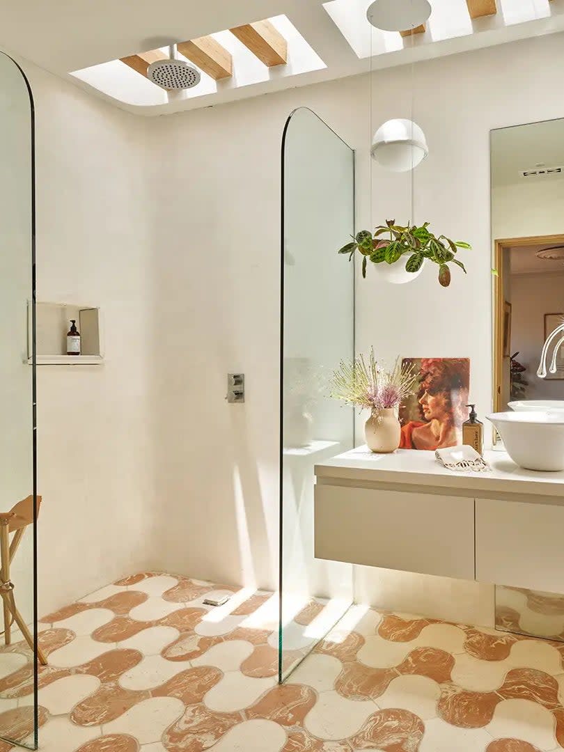 Bathroom with squiggly terracotta and white floor tile lit by a skylight. 