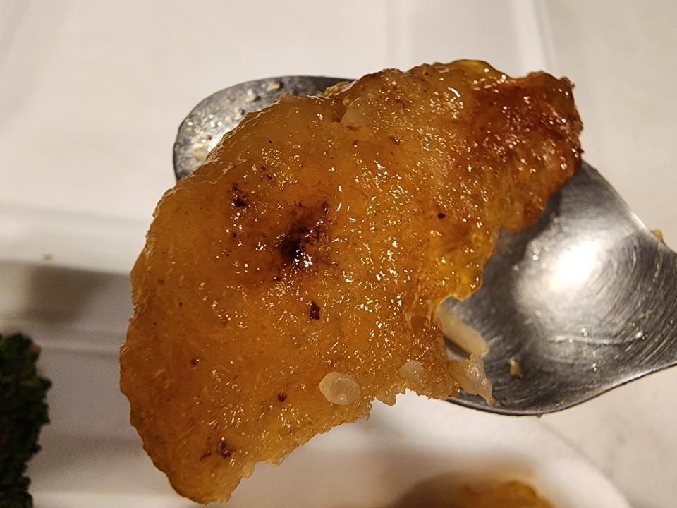 A spoon with a piece of honey-walnut shrimp on it