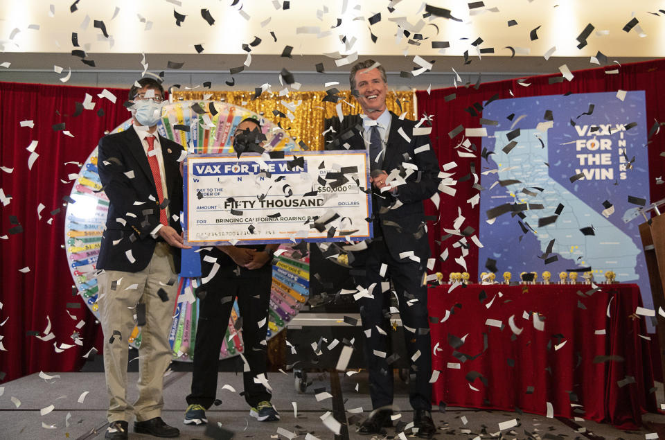 FILE - In this June 4, 2021, file photo, California Gov. Gavin Newsom, State Sen. Richard Pan, left, and UC Davis Assistant Nurse Manager Claudio Alvarado, center, hold a mock check as the state drew the first 15 winners to be awarded $50,000 for getting vaccinated against COVID-19, at the California Lottery Headquarters in Sacramento, Calif. As cases fall and states reopen, the potential final stage in the U.S. campaign to vanquish COVID-19 is turning into a slog, with a worrisome variant gaining a bigger foothold and lotteries and other inducements failing to persuade some Americans to get vaccinated. (Paul Kitagaki Jr./The Sacramento Bee via AP, File)