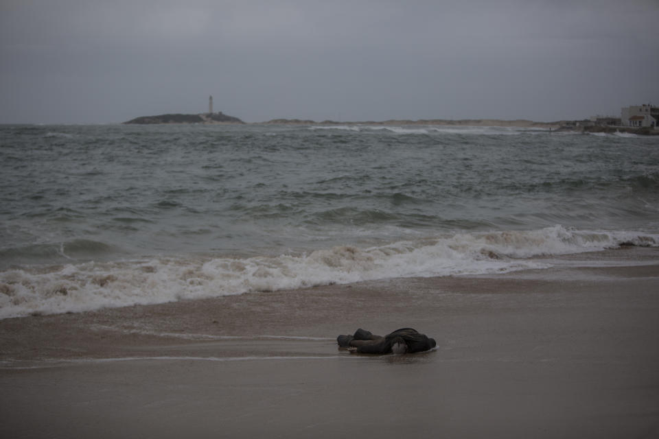 A body lies on the beach at the village of Canos de Meca, Spain, Thursday, Nov. 8, 2018, where seven were recovered from the sea after their vessel impacted rocks while trying to reach the coast. Migrants departing from North Africa travel on the Alboran Sea, part of the western Mediterranean route into Europe. (AP Photo/Javier Fergo)