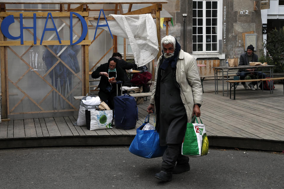 Homeless people arrive in the "Aurore" center for homeless and migrants in Paris, Thursday, April 2, 2020. Amid the coronavirus lockdown, charity workers at France's Aurore association, are preparing more than a thousand meals a day for migrants and the homeless on the half-abandoned grounds of a former Paris hospital whose patron saint was devoted to the poor. (AP Photo/Francois Mori)