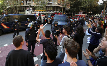 Protestors shout in front of a line of Spanish national police who surrounded the leftist Popular Unity Candidacy (CUP) party headquarters in Barcelona, Spain, September 20, 2017. REUTERS/Albert Gea