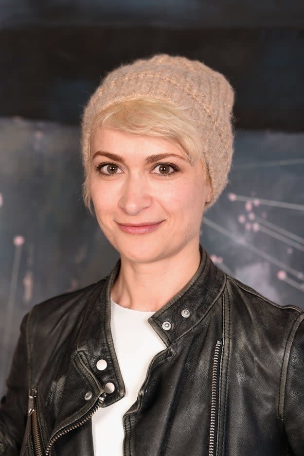 Woman in beanie and leather jacket smiling at a premiere event