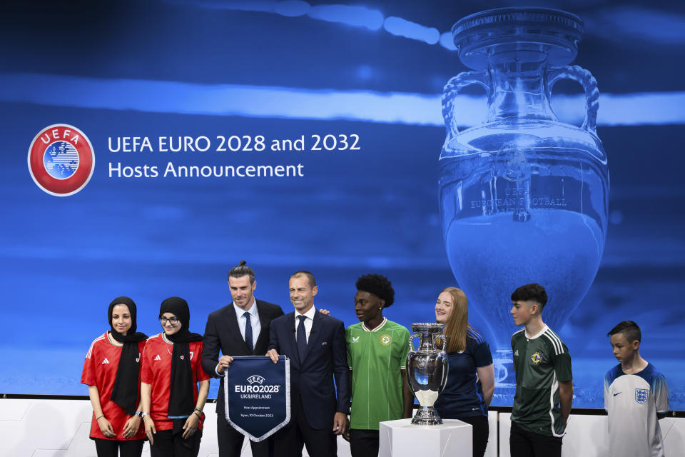 UEFA president Aleksander Ceferin, fourth left, shows the name of UK and Ireland elected to host the Euro 2028 fooball tournament with Gareth Bale, third left, Welsh soccer player and Ambassador during the the UEFA EURO 2028 and 2032 hosts announcement ceremony after the UEFA Executive Committee, at UEFA Headquarters, in Nyon, Switzerland, Tuesday, October 10, 2023. UEFA has decided the future of soccer’s European Championship for the next decade. The United Kingdom and Ireland will host in 2028 and an unusual Italy-Turkey co-hosting plan was picked for 2032. (Jean-Christophe Bott/Keystone via AP)