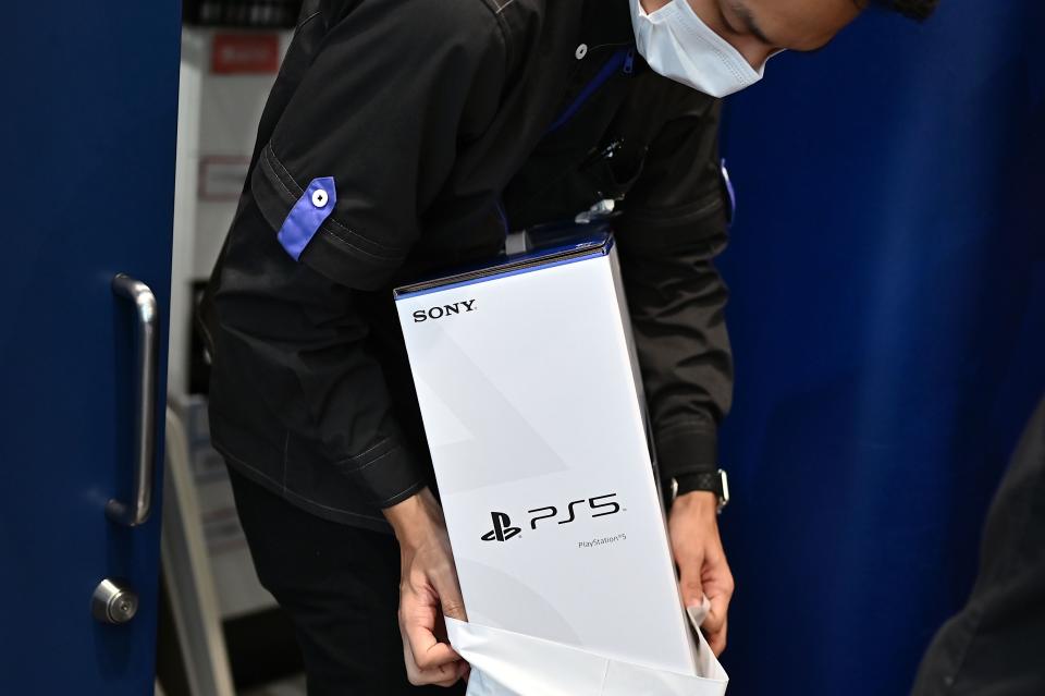 An employee prepares the new Sony PlayStation 5 gaming console for a customer on the first day of its launch, at an electronics shop in Kawasaki, Kanagawa prefecture on November 12, 2020. (Photo by CHARLY TRIBALLEAU / AFP) (Photo by CHARLY TRIBALLEAU/AFP via Getty Images)