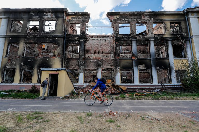 Un ciclista pasa junto a los restos de una escuela dañada por los ataques aéreos rusos en Kharkiv, en medio de la invasión rusa de Ucrania. 