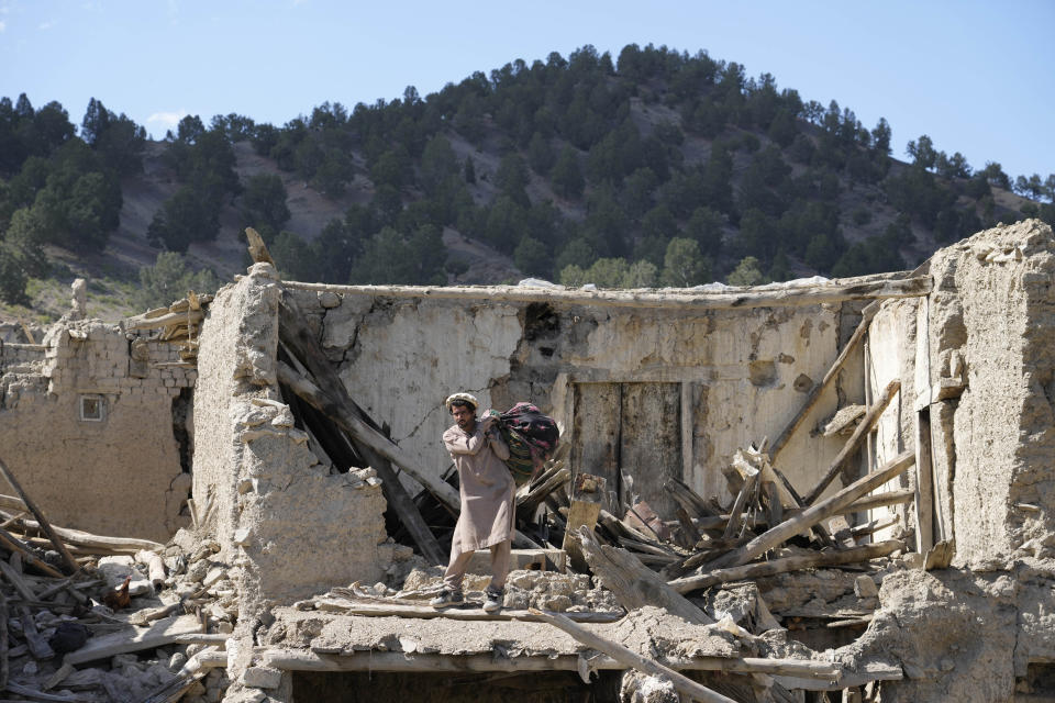 A man picks up belongings after an earthquake in Gayan village, in Paktika province, Afghanistan, Friday, June 24, 2022. A powerful earthquake struck a rugged, mountainous region of eastern Afghanistan early Wednesday, flattening stone and mud-brick homes in the country's deadliest quake in two decades, the state-run news agency reported. (AP Photo/Ebrahim Nooroozi)