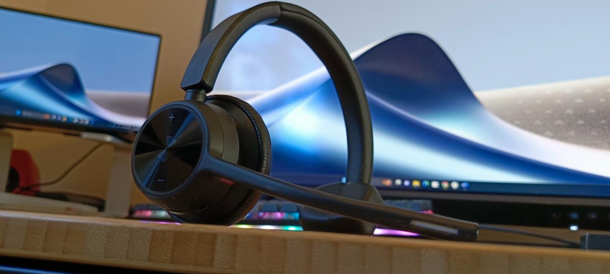  A Poly Voyager 4310 UC headset on a wooden desk. 