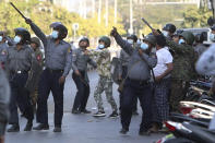 FILE - In this Feb. 15, 2021, file photo, a policeman aims a slingshot towards an unknown target during a crackdown on anti-coup protesters holding a rally in front of the Myanmar Economic Bank in Mandalay, Myanmar. The escalation of violence in Myanmar as authorities crack down on protests against the Feb. 1 coup is adding to pressure for more sanctions against the junta, as countries struggle over how to best confront military leaders inured to global condemnation.(AP Photo/File)