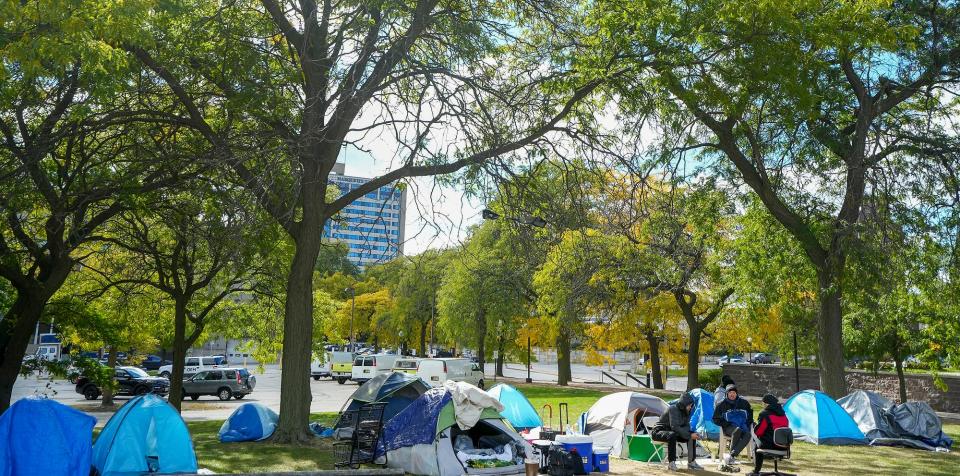 Men congregate around the encampment of tents Friday, Oct. 7, 2022, at MacArthur Square in Milwaukee.