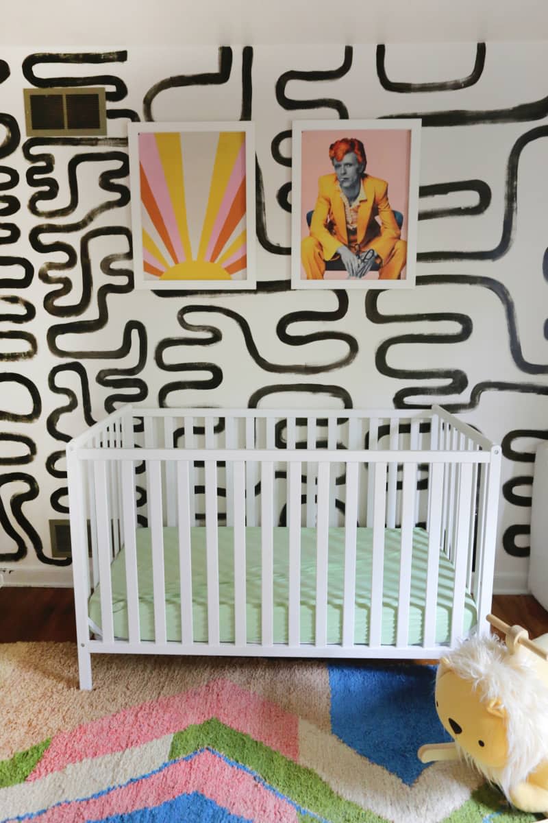 Black and white mural painted on wall behind baby crib.
