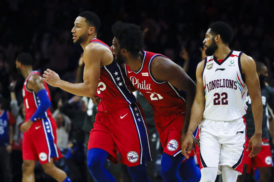 Philadelphia 76ers' Joel Embiid, center right, celebrates with Ben Simmons, center left, after he shot a 3-pointer to end the second quarter as Guangzhou Loong-Lions' CJ Harris, right, looks on during the first half of an NBA exhibition basketball game Tuesday, Oct. 8, 2019, in Philadelphia. (AP Photo/Matt Rourke)