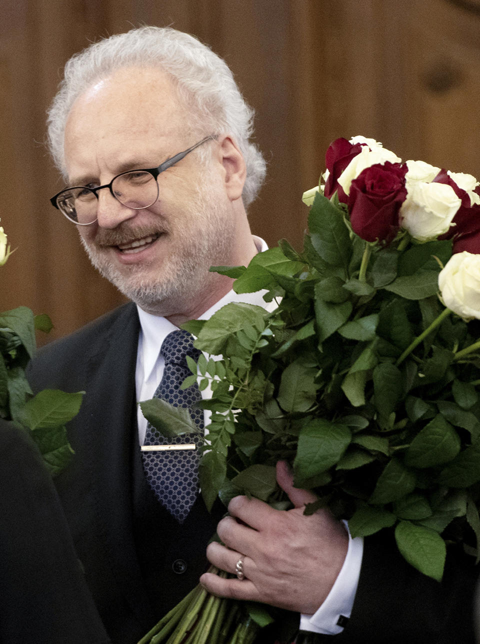 Newly elected Latvian President Egils Levits hold a bunch of flowers after lawmakers elected him in a parliament in Riga, Latvia, Wednesday, May 29, 2019. Levits received 61 votes already in the first round of voting, well above the 51 needed to win the election. (Vladislavs Proskins,/F64 Photo Agency via AP)