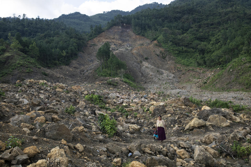 A woman and her son walk through the devastation caused by a mudslide triggered by Hurricane Eta, in Queja, Guatemala, Wednesday, July 7, 2021. Fifty-eight people disappeared in seconds in the Guatemalan town in November 2020. Forty homes were buried under tons of mud and dozens of others were left inaccessible. (AP Photo/Rodrigo Abd)