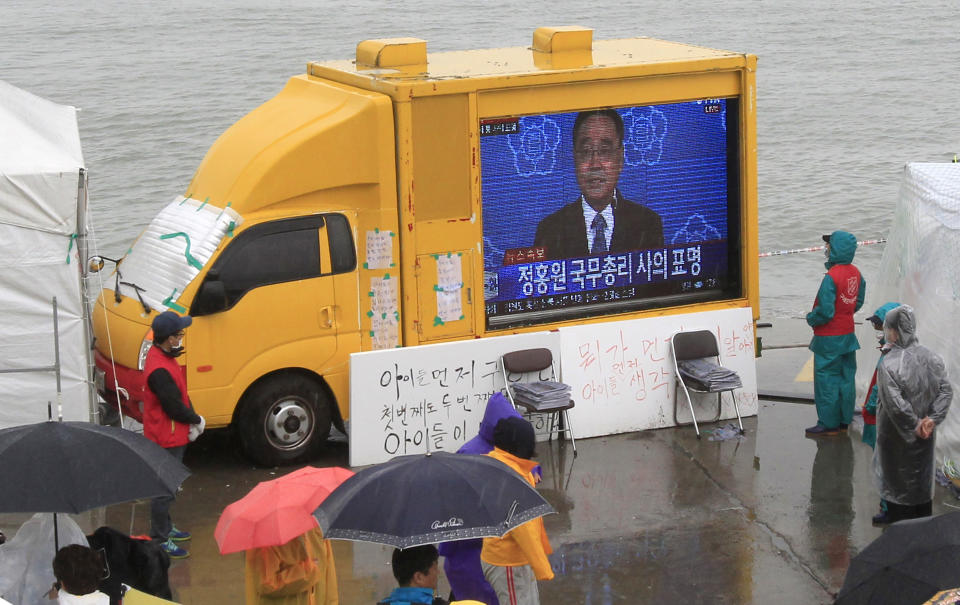 Relatives of passengers aboard the sunken ferry Sewol and onlookers watch a television news program showing South Korean Prime Minister Chung Hong-won offering his resignation at a port in Jindo, South Korea, Sunday, April 27, 2014. Chung offered to resign Sunday over the government's handling of the deadly ferry sinking, blaming "deep-rooted evils" and irregularities in a society for a tragedy that has left more than 300 people dead or missing and led to widespread shame, fury and finger-pointing. (AP Photo/Ahn Young-joon)