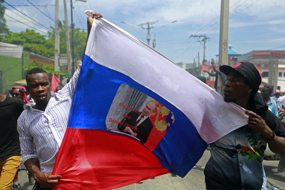 Anti-government demonstrators hold a Russian flag with a picture of Russian President Vladimir Putin that reads in Creole "Long live Putin. Down with Donald Trump" in Port-au-Prince, Haiti, Sunday, June 9, 2019. Protesters denouncing corruption paralyzed much of the capital as they demanded the removal of President Jovenel Moise. (AP Photo/Dieu Nalio Chery)