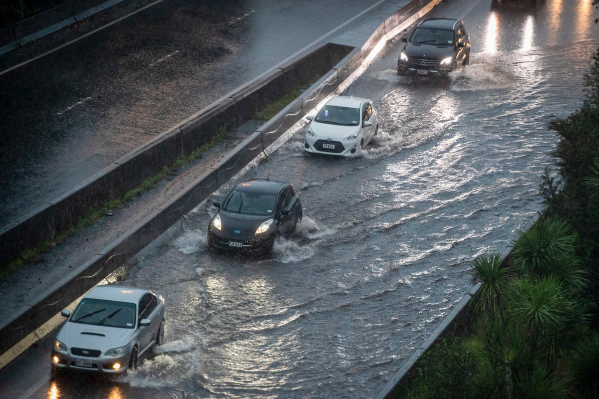 Cars move through water in the flooded streets of a motorway in central Auckland (AP)