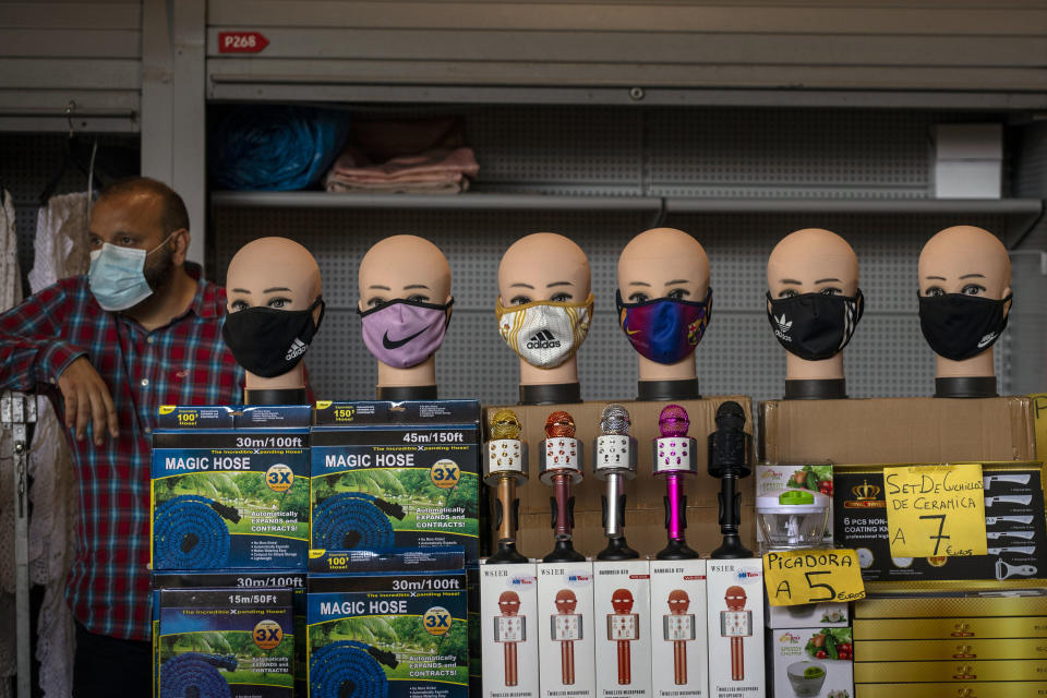 A vendor selling face masks waits for customers at a stall in a market in Barcelona on Wednesday, July 8, 2020. Spain's northeastern Catalonia region will make mandatory the use of face masks outdoors even when social distancing can be maintained, regional chief Quim Torra announced Wednesday. (AP Photo/Emilio Morenatti)