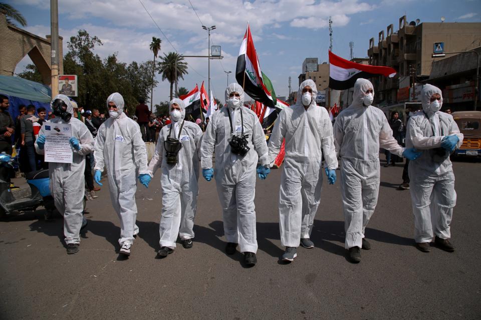 Anti-government protesters wear hazmat suits and gas masks during a rally in Baghdad, Iraq, Sunday, March 1, 2020. Iraqi student protesters converged on Baghdad's Tahrir Square, the epicenter of the five-month- anti-government protest movement, to voice their rejection of the country's proposed new prime minister. (AP Photo/Khalid Mohammed)