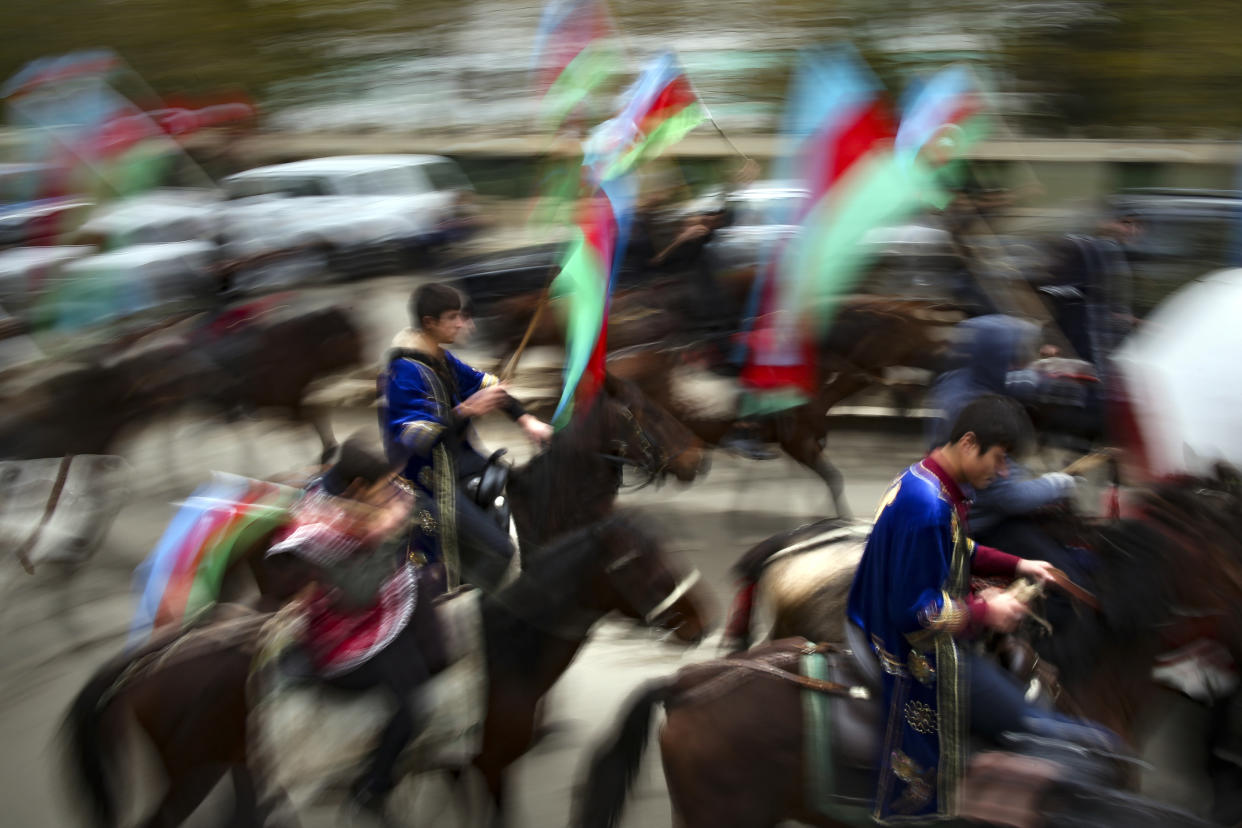 Azerbaijani with national flags ride horses as they celebrate the transfer of the Lachin region to Azerbaijan's control, as part of a peace deal that required Armenian forces to cede the Azerbaijani territories they held outside Nagorno-Karabakh, in Aghjabadi, Azerbaijan, Tuesday, Dec. 1, 2020. Azerbaijan has completed the return of territory ceded by Armenia under a Russia-brokered peace deal that ended six weeks of fierce fighting over Nagorno-Karabakh. Azerbaijani President Ilham Aliyev hailed the restoration of control over the Lachin region and other territories as a historic achievement. (AP Photo/Emrah Gurel