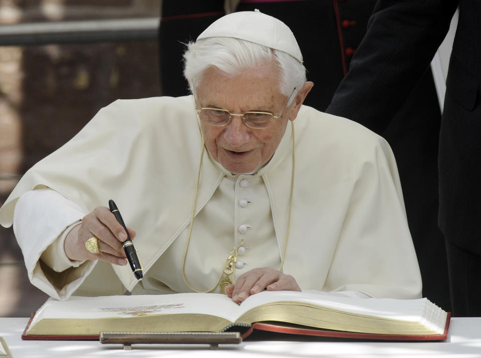 FILE - Pope Benedict XVI signs the golden book of Freiburg in front of the cathedral in Freiburg, Germany, on Sept. 24, 2011. When Cardinal Joseph Ratzinger became Pope Benedict XVI and was thrust into the footsteps of his beloved and charismatic predecessor, he said he felt a guillotine had come down on him. The Vatican announced Saturday Dec. 31, 2022 that Benedict, the former Joseph Ratzinger, had died at age 95. (AP Photo/Martin Meissner, File)