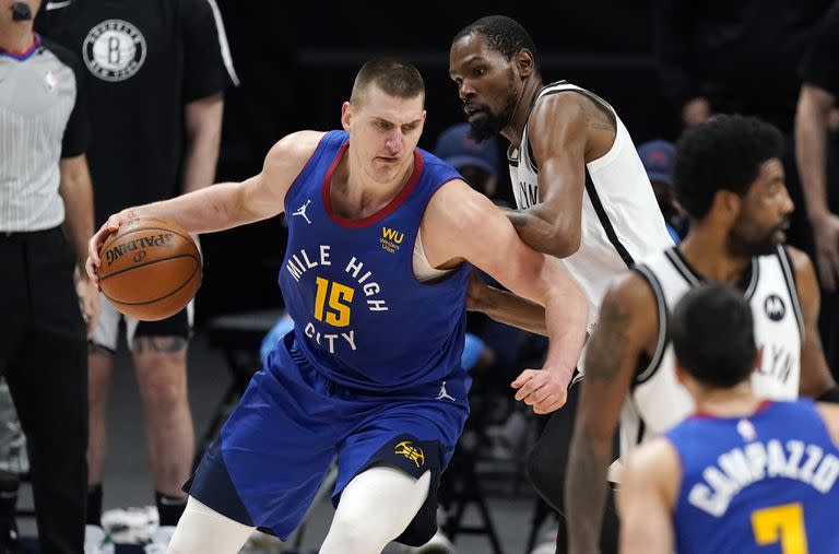 Nikola Jokic ataca el canasto ante Kevin Durant, mientras Facundo Campazzo observa. fue durante un partido entre Denver Nuggets y Brooklyn Nets de la última temporada de la NBA