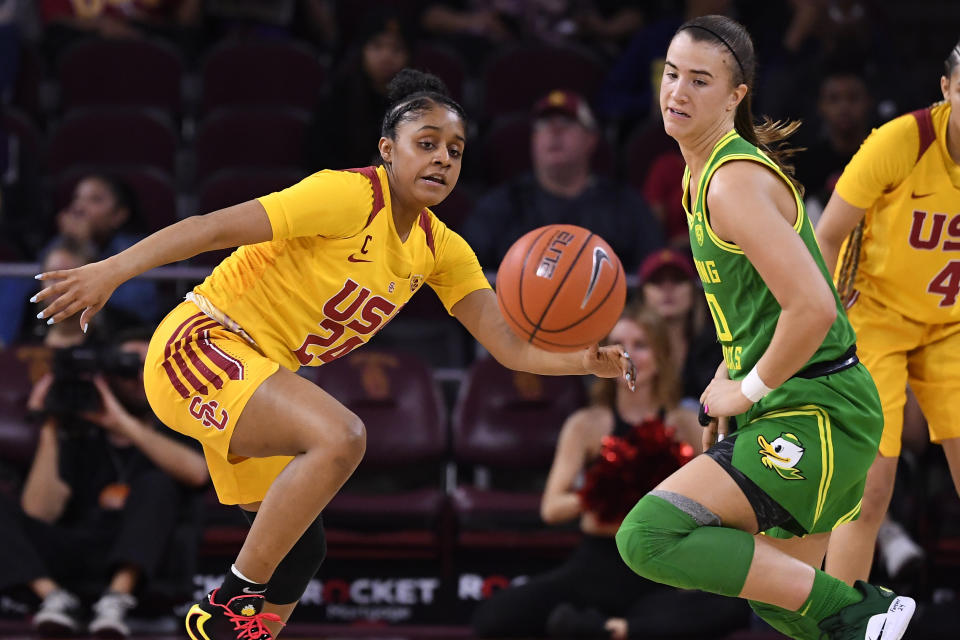 Southern California guard Desiree Caldwell left, and Oregon guard Sabrina Ionescu go after a loose ball during the first half of an NCAA college basketball game Sunday, Feb. 16, 2020, in Los Angeles. (AP Photo/Mark J. Terrill)