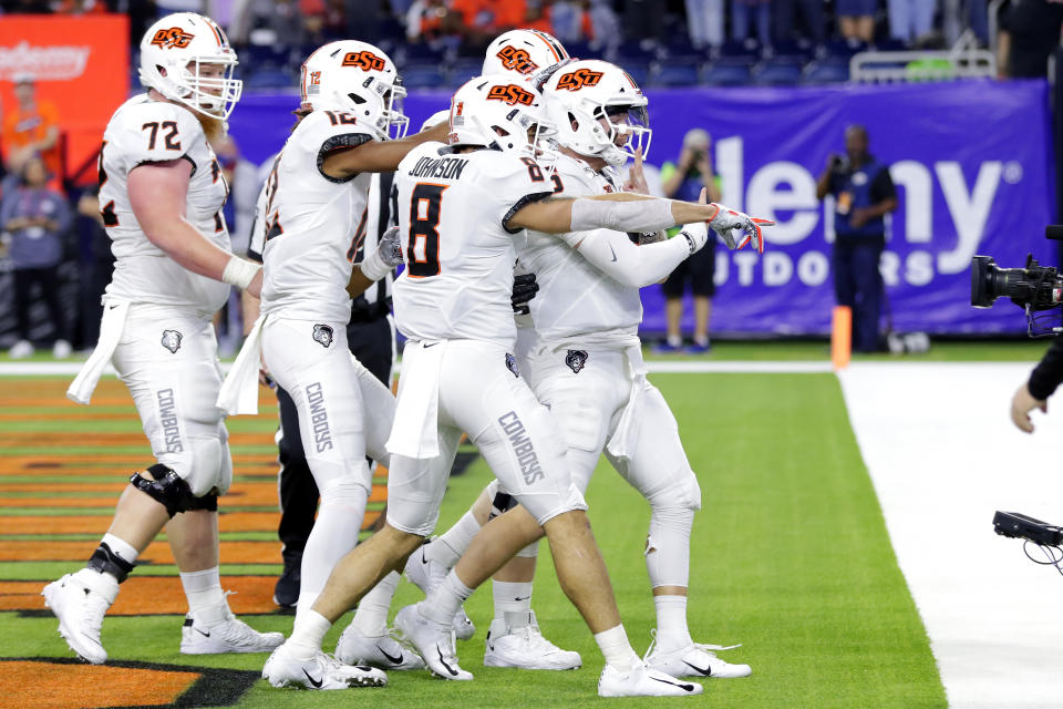 Oklahoma State players, led by quarterback Dru Brown, front, point at end zone camera as they celebrate a touchdown by Brown during the first half of the Texas Bowl NCAA college football game against Texas A&M on Friday, Dec. 27, 2019, in Houston. (AP Photo/Michael Wyke)