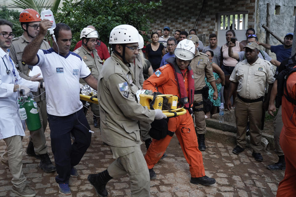 Firefighters accompany an injured child who was rescued from the rubble of two buildings that collapsed in the Muzema neighborhood, in Rio de Janeiro, Brazil, Friday, April 12, 2019. The collapse came in a western part of the city that was particularly hard hit by heavy rains this week that caused massive flooding. (AP Photo/Leo Correa)