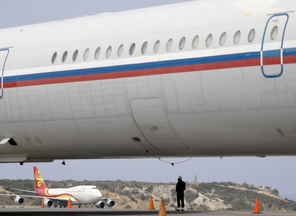 A Chinese airplane is framed by the fuselage of a Russian airplane at the Simon Bolivar International Airport in Maiquetia, near Caracas, Venezuela, Friday, March 29, 2019. Aid was unloaded from the Chinese plane in what Venezuelan officials said would be the first delivery of many from China, an ally of the government of President Nicolas Maduro. (AP Photo/Natacha Pisarenko)