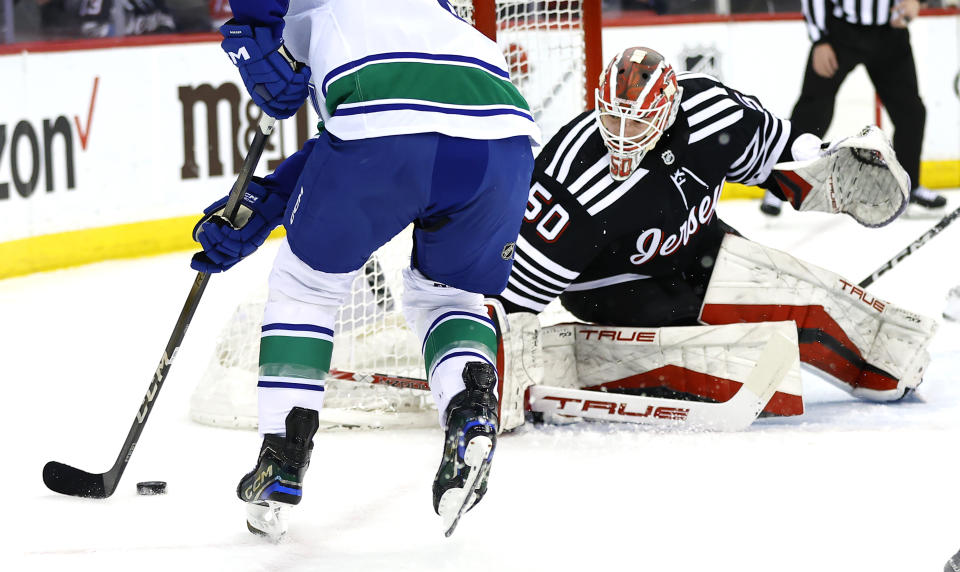 New Jersey Devils goaltender Nico Daws (50) defends against Vancouver Canucks right wing Brock Boeser, left, during the first period of an NHL hockey game, Saturday, Jan. 6, 2024, in Newark, N.J. (AP Photo/Noah K. Murray)