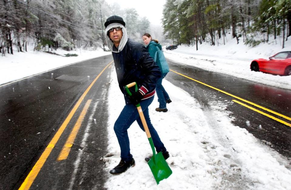 After lending her shovel to one motorist to move his stranded vehicle off of Avent Ferry Road in Raleigh, Ashley Jermusyk, rear, then leaves her shovel with another stranger, Sam Almheiri, a freshman at NC State and from Hawaii, front, on Thursday, February 13, 2014. He also had to leave his car overnight on Wednesday and walk home. They made arrangements for her to pick it up at a later time. Area residents begin to dig out on the second day of snow in the Triangle region. Corey Lowenstein/clowenst@newsobserver.com