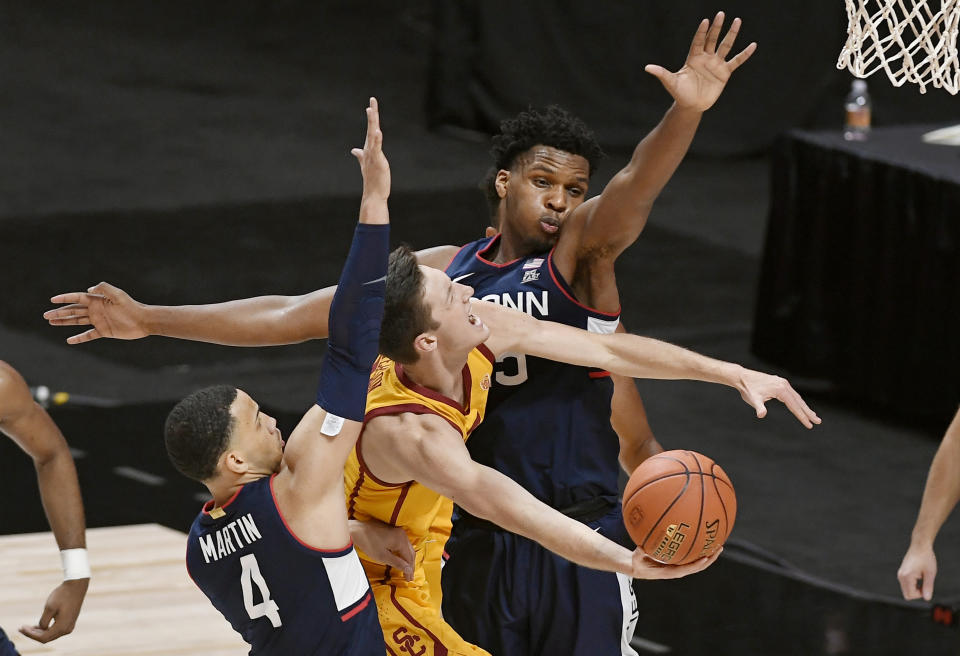 Southern California's Drew Peterson, center, shoots under pressure from Connecticut's Tyrese Martin, left, and Josh Carlton during the second half of an NCAA college basketball game Thursday, Dec. 3, 2020, in Uncasville, Conn. (AP Photo/Jessica Hill)