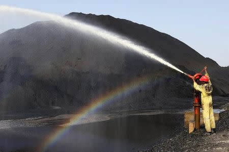 A worker sprays water over piles of coal at Mundra Port Coal Terminal in the western Indian state of Gujarat April 2, 2014. REUTERS/Amit Dave/Files