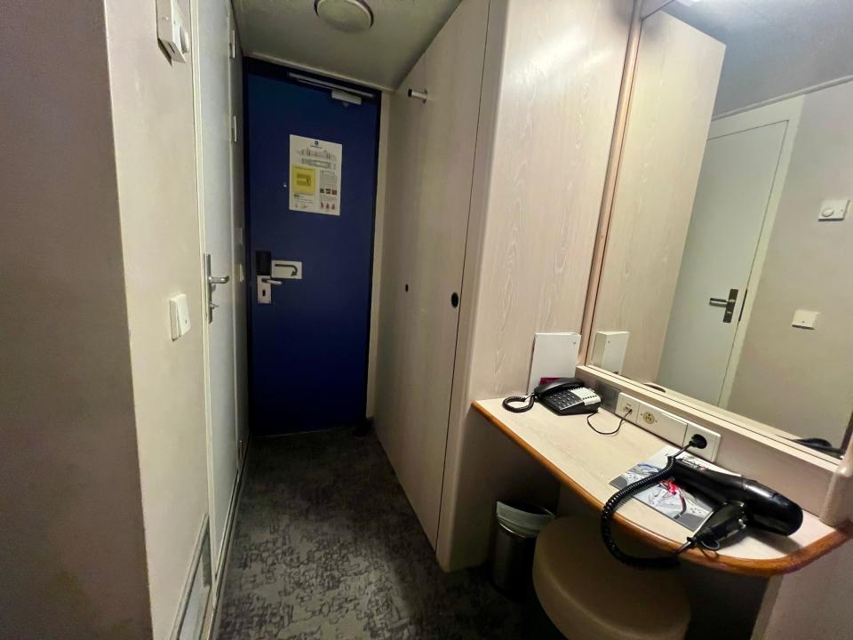 The hallway with the closet and desk with a hair dryer.