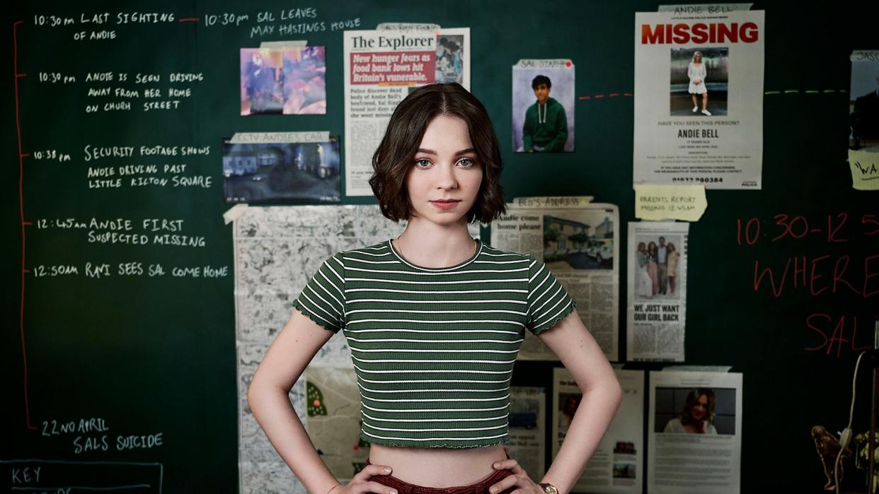  A Good Girl's Guide to Murder star Emma Myers in front of a board of clues. 