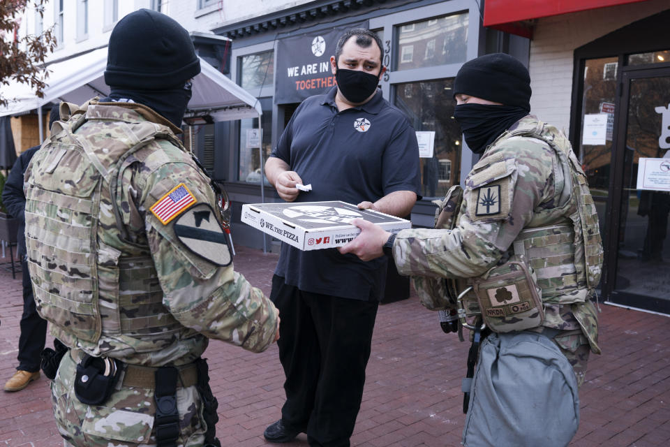 Robert Earley, center, general manager at We The Pizza, hands donated pizza to members of the National Guard from New York, Saturday, Jan. 16, 2021, in Washington, as security is increased ahead of the inauguration of President-elect Joe Biden and Vice President-elect Kamala Harris. (AP Photo/Jacquelyn Martin)